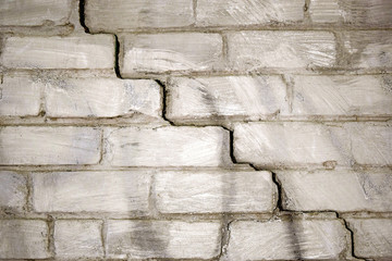 diagonal deep crack on old brick wall close up, texture and background, cracked white brick wall