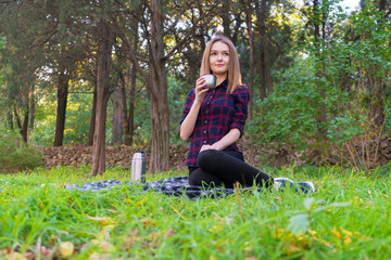Obraz premium Girl in a plaid shirt is resting in a park on a plaid