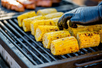 BBQ corn on an open grilles fire.Hand in glove overtakes pumpkin corn