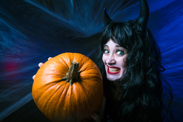 young woman in halloween costume posing with pumpkin