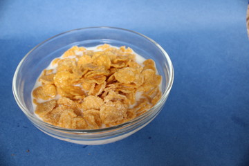 cornflakes in bowl plate on blue background