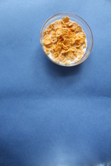 cornflakes in bowl plate on blue background