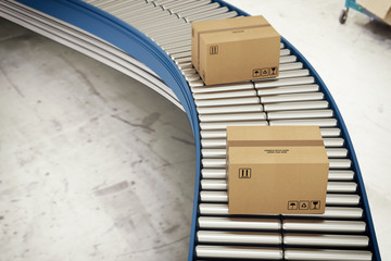 Cardboard boxes on conveyor rollers ready to be shipped by courier for distribution