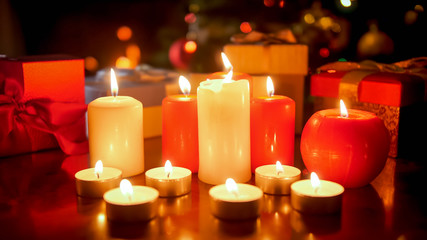 Beautiful background with burning candles against glowing Christmas tree at night