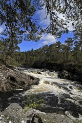 Fototapeta na wymiar wild mountain river with white water and cascades in Scotland
