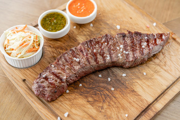 Hot grilled whole Denver steak with Pickled cabbage and two sauces. Serving on a wooden Board. Barbecue restaurant menu. a series of photos of different meats