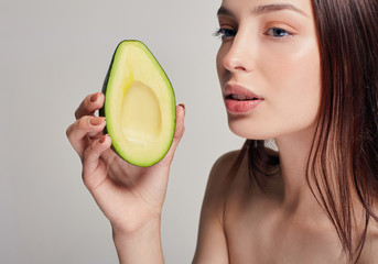Profile side photo portrait of brown-haired nude lady with perfect pure shine skin with avocado in the hand