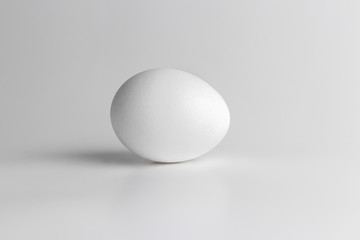 one chicken raw egg on grey neutral background. Close-up and side view