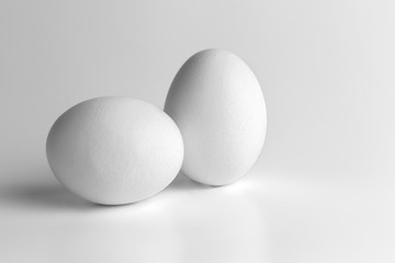 two chicken raw eggs on grey neutral background. Close-up and side view