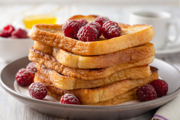 French toasts with powdered sugar and fresh raspberries on wooden table. Selective focus.