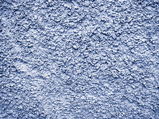 Blue-gray stucco with a chaotic convex pattern. The stone wall is covered with new rough plaster