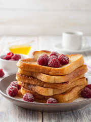 French toasts with powdered sugar and fresh raspberries on wooden table. Selective focus.