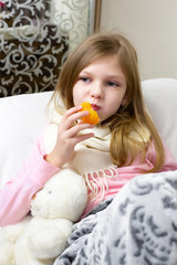 Obraz na płótnie Canvas A sick little girl takes medication and eats fruit.