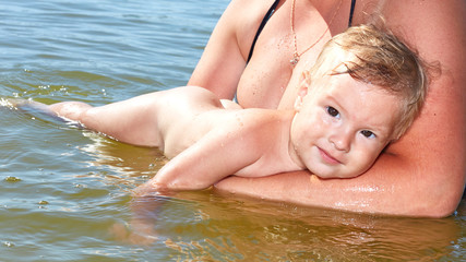 The baby lies in the water in her mother’s arms