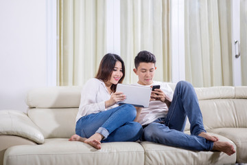 Couple enjoying leisure time with tablet and phone