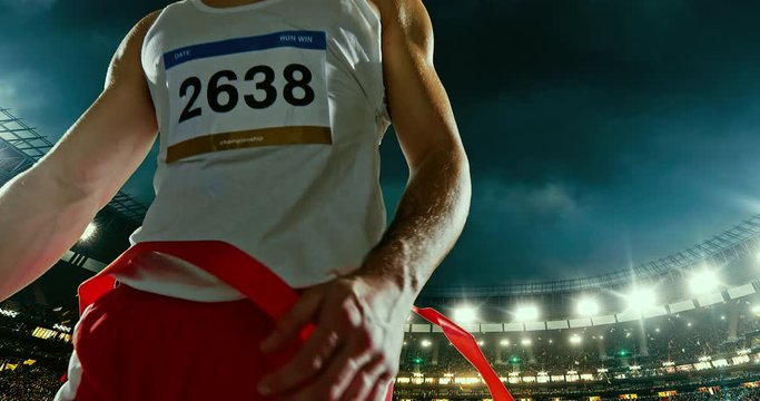 Male track and field runner crosses finishing line on the professional sports arena. The man is happy, smiling with his arms raised. Arena and people on it are made in 3D and animated.