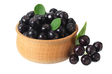 Chokeberry in wooden bowl isolated on white background. Black aronia