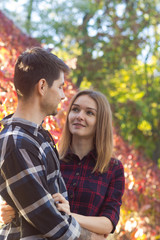 Fototapeta premium man and woman in plaid shirts in the autumn park. Happy couple in love
