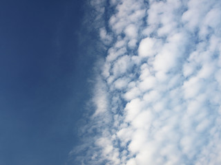 Summer background with white flying clouds on blue sky. Romantic natural heaven backdrop. 