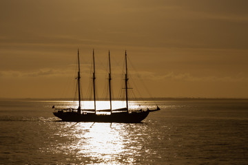 Obraz premium Four masts sailing ship at sea photo taken against sun