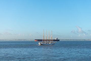 Four masts sailing ship and cargo ship at sea