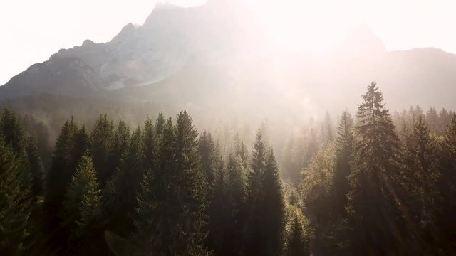 Zugspitz mountain early morning with sunrise and misty fog scenery, descent light drone perspective with fog and morning dust