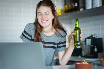 Young woman using laptop with headphones in the kitchen