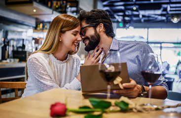 Birthday present for a girlfriend. Romantic couple sitting in the cafe and drinking red wine. Dating, love, relationships