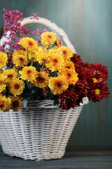 Fototapeta na wymiar Autumn background with beautiful flowers in basket on the table.
