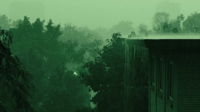 An erie green sky during a thunderstorm with heavy rain