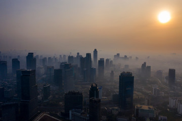 Skyscrapers covered by air pollution at sunset