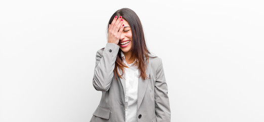 young pretty woman laughing and slapping forehead like saying d‚Äôoh! I forgot or that was a...