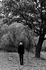 Blondy girl in black sweater and beret stands in the autumn in the park