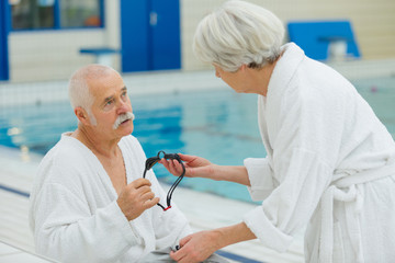 elderly couple lying on a pool deck