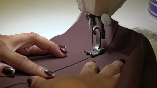 Professional seamstress starting a new seam on a brown dress