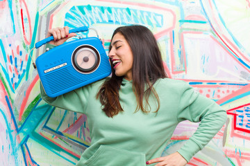 young pretty woman with a vintage radio against graffiti wall