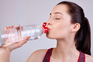 athletic beautiful girl, dark brown hair with full lips with a bottle of water in her hand.