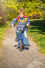 Little boy rides a bicycle in the autumn park.