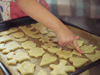 a child at home cuts out cookie cutters.
