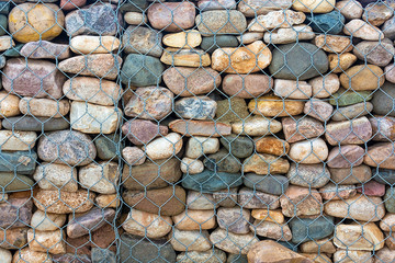 stonework shore strengthening. Close-up. Abstract background. stones in iron nets protect the beach and the shore from wave erosion during storms.