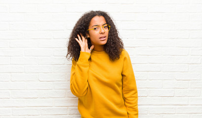 young black woman looking serious and curious, listening, trying to hear a secret conversation or...