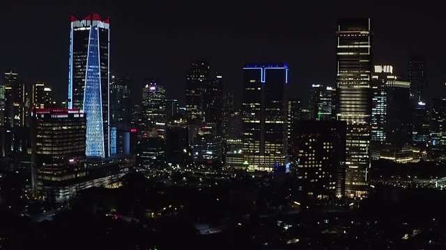 JAKARTA, Indonesia - October 07, 2019: Exotic aerial view of business district with modern office buildings and night lights. Shot in 4k resolution from a drone flying forwards