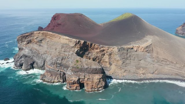 A lot of grottos in rocky cliff of Capelinhos. Turquoise sea at the foot of vlocano. Faial, Azores