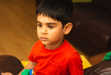 4-5 years Indian boy in shirt open eyes facing towards camera looking sideways portrait inside home 