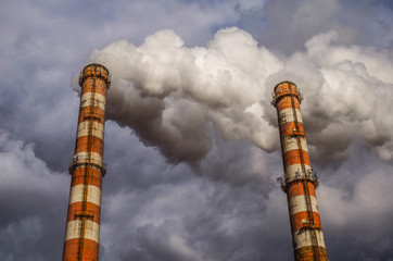 Air pollution by smoke coming out of two factory chimneys. Environmental issue related to air pollution.