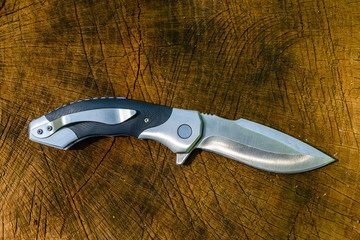 Folding knife on the rustic wooden background