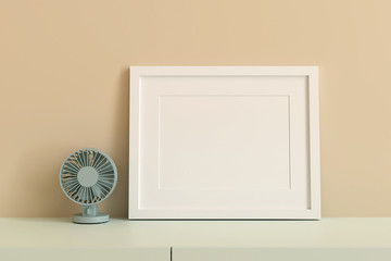 empty white picture frame for insert text or image inside with fan decorate on orange pastel color..