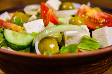 Ceramic plate with greek salad on wooden table