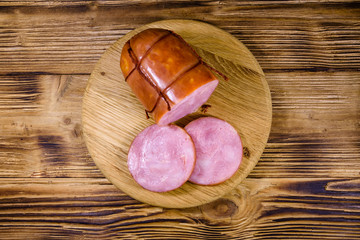 Cutting board with sliced sausage on wooden table. Top view