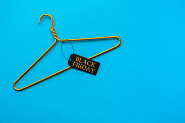 Empty gold hanger rack with label tag on bright blue color table background, male female retail...